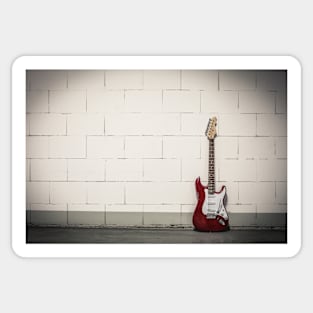 Red electric guitar against white brick wall Sticker